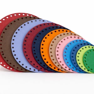 May include: A collection of colorful, round, crochet bag bases in various sizes. The bases are made of a sturdy material and feature evenly spaced holes around the perimeter for easy stitching. Colors include red, brown, blue, orange, pink, and green.