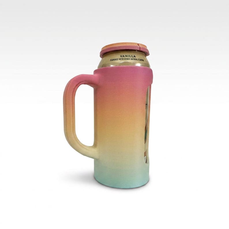 May include: A colorful can cooler with a handle, featuring a gradient of pink, yellow, and teal. The cooler holds a can with the word "VANILLA" visible. The design resembles a mug, providing a comfortable grip for the user.