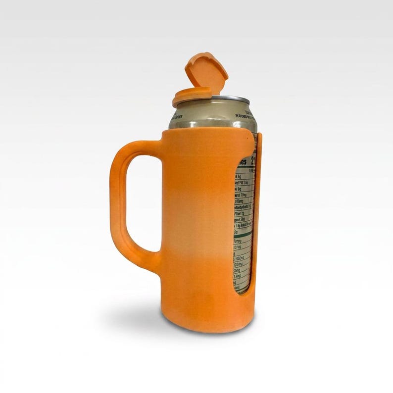 May include: Orange plastic can holder with a handle, designed to hold a standard beverage can. The holder has an attached lid that can be opened and closed. The can's label is visible through a cutout on the side. The holder is designed to keep the beverage cold.