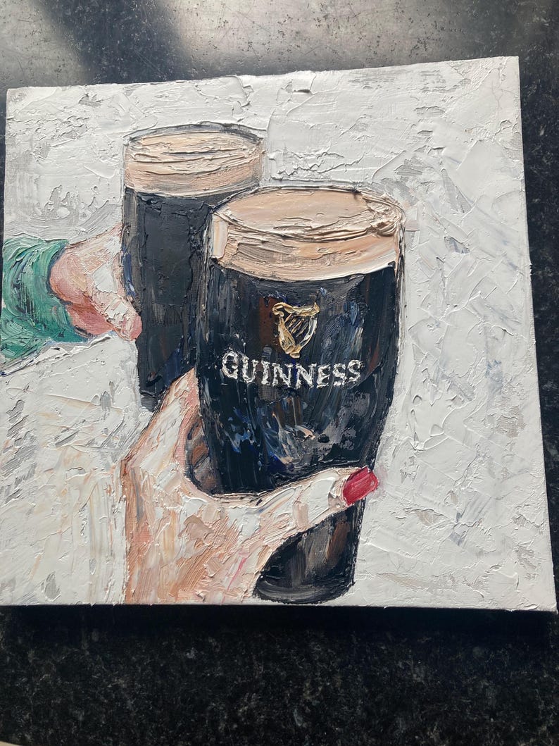 May include: An oil painting on canvas featuring two dark stout beers in pint glasses with thick creamy heads. The glasses are held by hands, one with red nail polish, against a textured white background. The Guinness logo is visible on the glass.