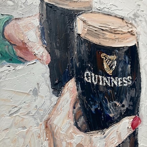 May include: An oil painting with thick impasto texture depicting two dark stout glasses with creamy tan heads. One glass features the gold harp logo and the white text GUINNESS. The scene shows two hands holding the glasses in a toast against a white background.