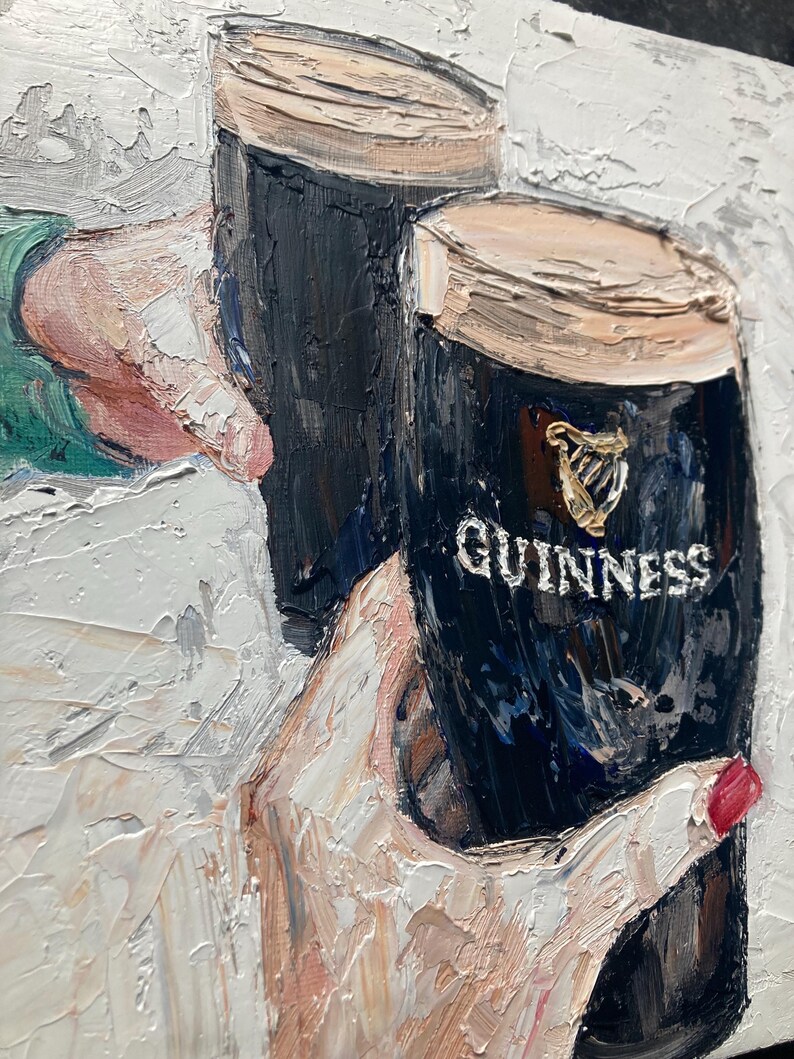 May include: An oil painting with thick impasto texture depicting two dark stout glasses with creamy tan heads. One glass features the gold harp logo and the white text GUINNESS. The scene shows two hands holding the glasses in a toast against a white background.