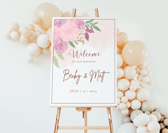 Peut inclure: Panneau de bienvenue de mariage sur un chevalet. Le panneau présente des illustrations florales dans des tons roses et violets, avec les mots "Bienvenue à notre mariage" et les noms "Becky & Matt" ainsi que la date du 15 juillet 2023.
