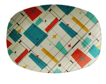 May include: A white oval serving platter with a geometric pattern in shades of red, yellow, blue, and teal. The pattern features intersecting lines and squares.