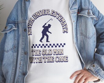 May include: White t-shirt with the text "NEVER UNDERESTIMATE THE OLD MAN WITH THE CANE" in blue. The shirt features a silhouette of an elderly person with a cane. The shirt is worn with a blue denim jacket.