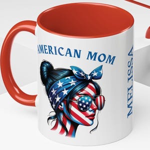May include: White ceramic mug with a red rim. The mug features a graphic of a woman with an American flag bandana and sunglasses. The text "American Mom" is printed in blue on the mug. The name "Melissa" is printed vertically on the right side of the mug.