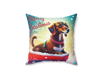 Può includere: Un cuscino quadrato con un design natalizio festoso che presenta un bassotto marrone e bianco seduto su una slitta rossa. Lo sfondo è un design in stile acquerello blu e verde con fiocchi di neve. Il testo "Merry Christmas" è scritto in rosso sul cuscino.