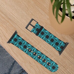 May include: Two-piece watch band with a teal and black buffalo plaid pattern. The band features a repeating black cat silhouette design. The watch band is made of a durable material and has a black buckle.