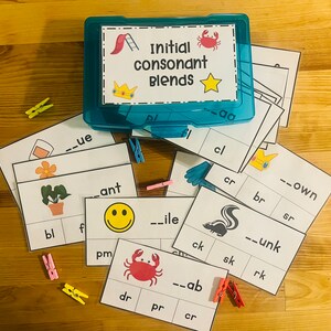 May include: A set of educational flashcards for learning initial consonant blends. The cards feature colorful illustrations and the words "Initial consonant blends" in a blue box. The cards are arranged on a wooden surface with clothespins.