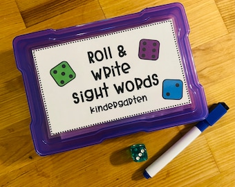 May include: A purple plastic storage box with a white card that says "Roll & Write Sight Words Kindergarten". There are three dice with different colored dots on them. One die is green, one is purple, and one is blue.