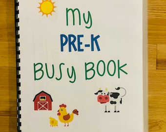 May include: A white binder with a clear plastic cover. The cover has a yellow sun, green text that says "my PRE-K BUSY BOOK", a red barn, a yellow chick, a yellow chicken, and a black and white cow.