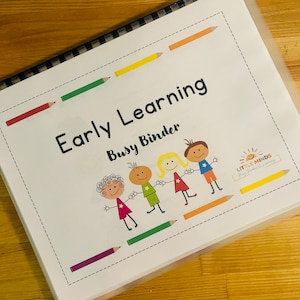 May include: A white binder with the title "Early Learning Busy Binder" and a colorful illustration of four children holding hands. The binder has a black and white checkered spine and a clear plastic cover. The text "Little Minds Busy Builders of Learning" is also visible on the cover.