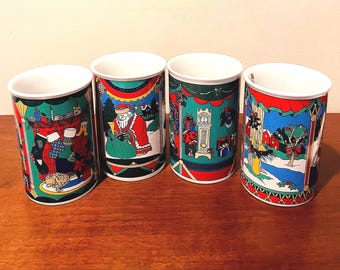 May include: Four ceramic Christmas mugs with festive designs. Each mug features a different holiday scene, including Santa Claus, a fireplace, and a winter landscape. The mugs have a white interior and are decorated with red, green, and gold accents.