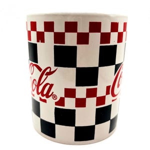 May include: A ceramic Coca-Cola mug with a checkered pattern in red, black, and white. The Coca-Cola logo is printed in red on the side of the mug. The mug is cylindrical and has a glossy finish.