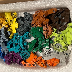 Op de afbeelding: Assortiment van kleurrijke plastic bouwstenen in verschillende vormen en maten. De blokken zijn in tinten groen, blauw, paars, oranje, geel en grijs.