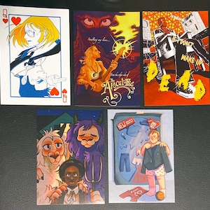 Peut inclure: Ensemble de cinq cartes illustrées présentant une variété de personnages et de scènes. Les cartes sont imprimées sur du papier cartonné blanc et ont une finition brillante. La première carte représente une femme portant des lunettes et un cœur rouge. La deuxième carte représente une femme jouant de la guitare avec le texte "Singing my love... from the other side of the Apocalypse". La troisième carte représente une personne avec un cœur rouge et le texte "If I don't wake up DEAD". La quatrième carte représente un lama blanc, un monstre violet et une personne avec une fourche. La cinquième carte représente une personne portant une chemise bleue et un pantalon rose tenant une veste bleue avec le texte "NEW OUTFIT PACK".