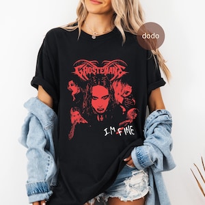 Puede incluir: Camiseta negra con un gráfico rojo. El gráfico presenta la palabra "Ghosteman" sobre una imagen central de una cara rodeada de otras caras. El texto "I'M FINE" está debajo. La camiseta tiene mangas cortas.