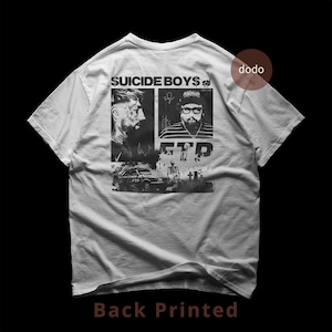 May include: White t-shirt with a black graphic print on the back. The print includes two portraits, the text "SUICIDE BOYS$" and "FTP", and a car image. The words "Back Printed" are at the bottom of the shirt.