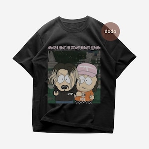 Può includere: T-shirt nero con una grafica a cartoni animati di due personaggi con espressioni sorprese. Il testo "SUICIDEBOYS" è arcuato sopra la grafica. Un personaggio tiene in mano una pistola. L'altro indossa un cappello rosa e una maglietta arancione.