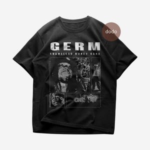 May include: Black t-shirt with the word "GERM" in white, above "SHAMELESS MONEY GANG". The shirt features a collage of black and white images. A brown circle with the word "dodo" is in the upper right corner.