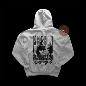 May include: A light gray hoodie with a hood and long sleeves. The back of the hoodie features a black and white graphic with the words "PEEP SHOW" above an image and the text "COME OVER WHEN YOU'RE SOBER MEET IN HEAVEN" with rose illustrations.