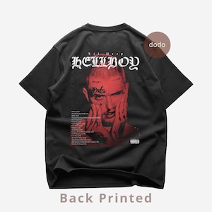 May include: Black t-shirt with a red graphic of a person's face and the word "HELLBOY" in white gothic lettering. The shirt also features a list of song titles and the text "Back Printed".