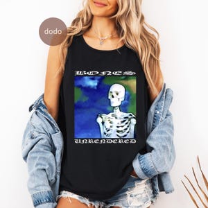Könnte beinhalten: Schwarzes Tanktop mit einem Skelett-Grafik und den Worten "BONES UNRENDERED" in einer gotischen Schriftart. Das Skelett ist vor einem blau-grünen Hintergrund platziert. Das Tanktop ist ärmellos.