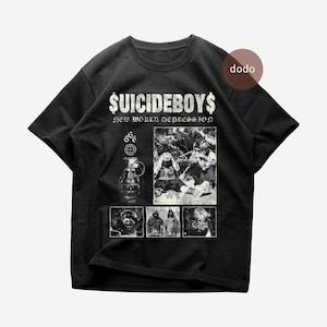 Op de afbeelding: Zwart T-shirt met de tekst "$UICIDEBOYS$" en "NEW WORLD DEPRESSION". Het shirt heeft grafische afbeeldingen van een granaat, een wereldbol en meerdere zwart-wit afbeeldingen. Het T-shirt heeft een ronde hals en korte mouwen.