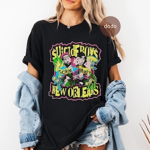 May include: Black t-shirt featuring a colorful graphic design with the text "SUICIDEBOYS" in yellow and green, along with the names "SCRIM" and "Ruby". The words "NEW ORLEANS" are also displayed in yellow.