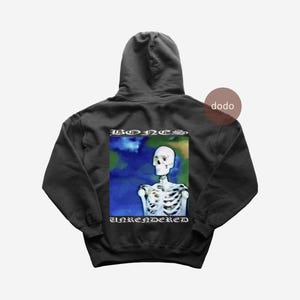 Könnte beinhalten: Schwarzer Kapuzenpullover mit einem Skelett-Grafik auf der Rückseite. Das Skelett ist vor einem blau-grünen Hintergrund platziert. Die Wörter "BONES" und "UNRENDERED" sind oberhalb und unterhalb der Grafik in Weiß gedruckt.