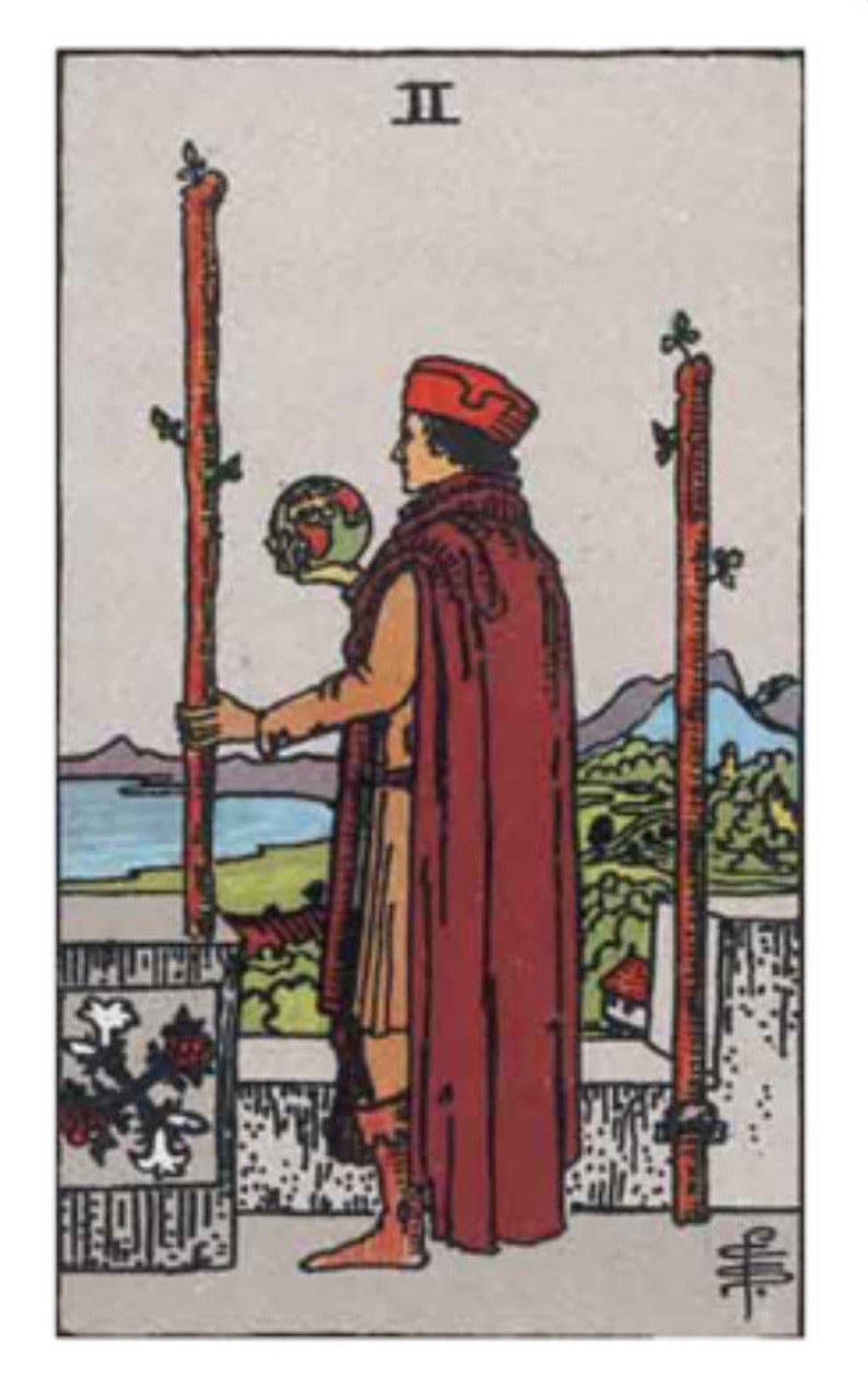 May include: A tarot card illustration featuring a figure in a red robe and cap standing on a stone balcony. The figure holds a small globe in one hand and rests the other on a tall wooden staff. A second staff stands nearby. The Roman numeral II is at the top.