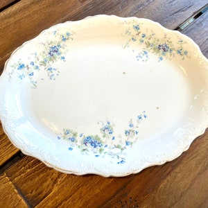 May include: White oval serving platter with a scalloped edge and a delicate floral pattern in shades of blue and green.