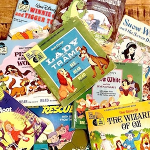 May include: A collection of vintage Disney storybook records, including "Lady and the Tramp," "Snow White," and "The Wizard of Oz." The covers feature colorful illustrations and text, with a retro aesthetic.