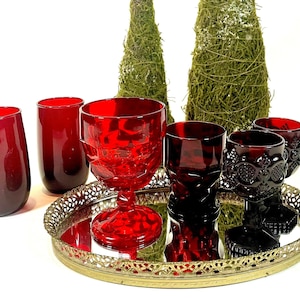 May include: Set of six red glass cups and goblets on a gold mirrored tray. The goblets have a textured design and the cups are smooth.