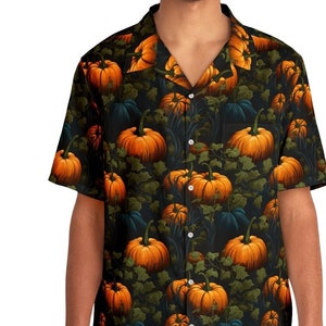 Può includere: Una camicia nera a maniche corte con bottoni e un motivo di zucche arancioni su uno sfondo verde scuro.