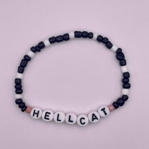May include: Black and white beaded bracelet with the word "HELLCAT" spelled out in white beads.