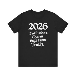 May include: Black t-shirt with white text. The text includes the year "2026" above the phrase "I Will Embody. Charm Built From Truth." A crew neck, short-sleeved shirt.