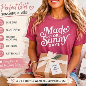 May include: A dark pink short-sleeved t-shirt with white text that reads Made for Sunny Days. The shirt is paired with a brown gift box tied with a white ribbon and a tag that says Sending you sunshine with a small pink heart icon.
