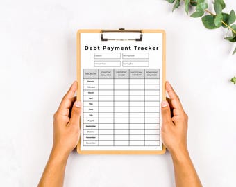 May include: A wooden clipboard with a printed "Debt Payment Tracker" form. The form includes fields for creditor, interest rate, minimum payment, and starting balance. The tracker has spaces for monthly payment tracking. The clipboard is held by two hands.