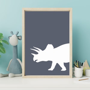 May include: A white silhouette of a triceratops dinosaur on a dark blue background. The silhouette is in a simple, modern style, perfect for a nursery or child's room.