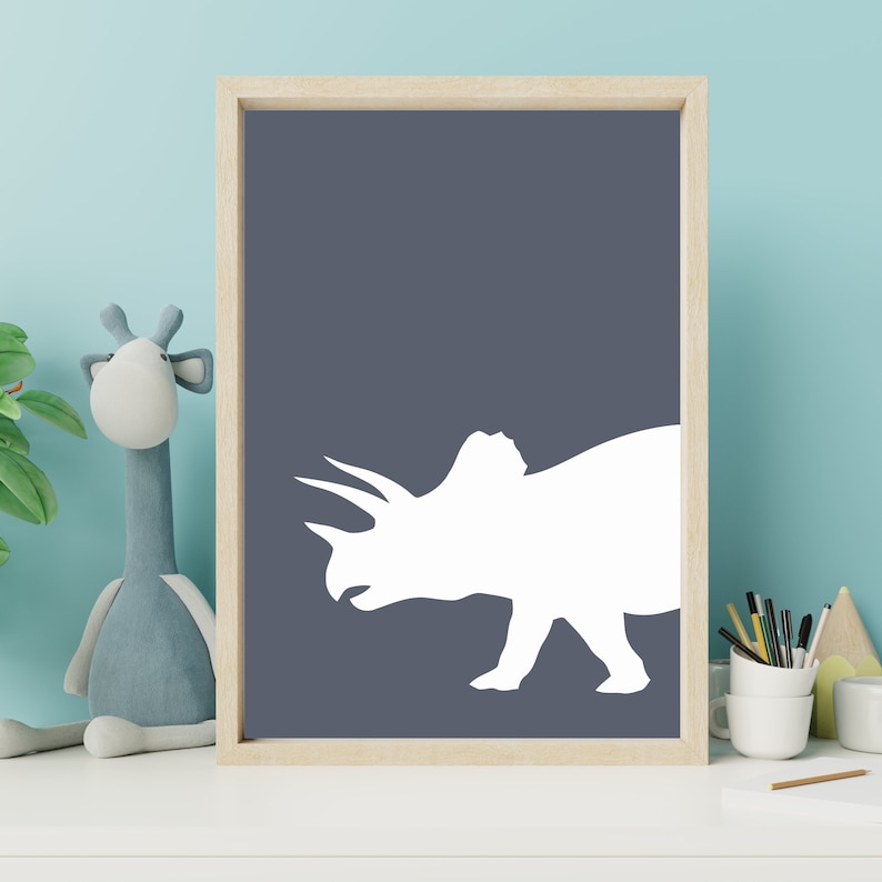 May include: A white silhouette of a triceratops dinosaur on a dark blue background. The silhouette is in a simple, modern style, perfect for a nursery or child's room.
