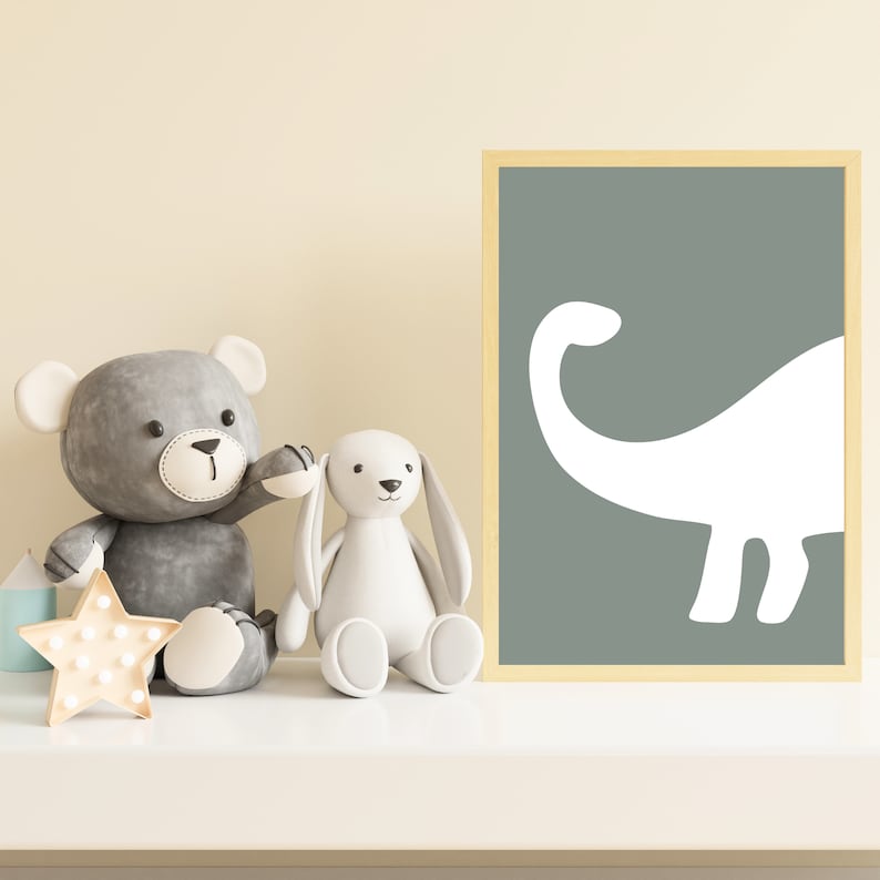 May include: A gray teddy bear and a white bunny rabbit plush toy sit on a white shelf in front of a framed print of a white dinosaur silhouette on a sage green background.