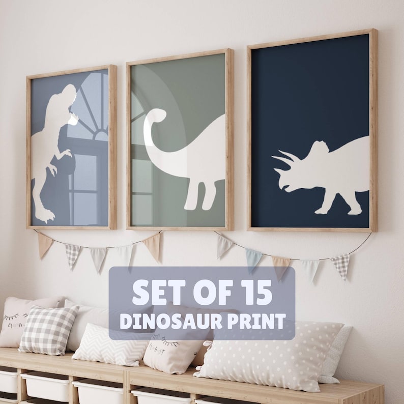 May include: Set of three framed dinosaur silhouette prints in blue, green, and navy blue. The prints feature a Tyrannosaurus Rex, a Brachiosaurus, and a Triceratops. The text "SET OF 15 DINOSAUR PRINT" is visible below the prints.