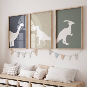 May include: Three framed prints of dinosaur silhouettes on a light green, light brown, and dark blue background. The prints are hanging on a white wall above a wooden bench with pillows.