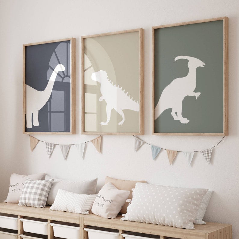 May include: Three framed prints of dinosaur silhouettes on a light green, light brown, and dark blue background. The prints are hanging on a white wall above a wooden bench with pillows.