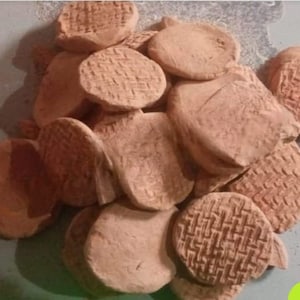 May include: A pile of terracotta clay discs, some with a woven pattern, others smooth. The discs are various sizes and shapes, with a light brown colour.