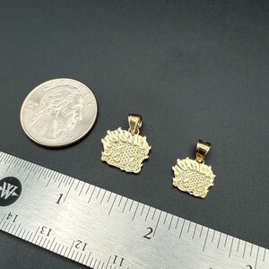 May include: Two gold pendants, one larger than the other, with a detailed design. The pendants are shown next to a ruler and a US quarter for size comparison.