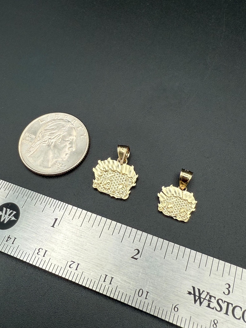 May include: Two gold pendants, one larger than the other, with a detailed design. The pendants are shown next to a ruler and a US quarter for size comparison.