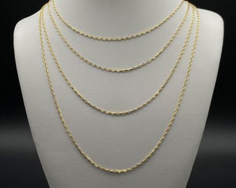 Può includere: Cinque catene d'oro di diverse lunghezze esposte su un busto di manichino bianco. Le catene sono tutte dello stesso stile, con un anello delicato di forma ovale.