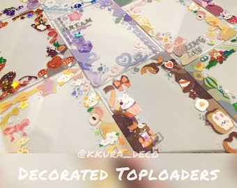 May include: A collection of clear, decorated toploaders with various colorful designs. Some toploaders feature text that reads "DREAM" and "SPRING DAY". The decorations include bows, hearts, clouds, and cartoon characters.